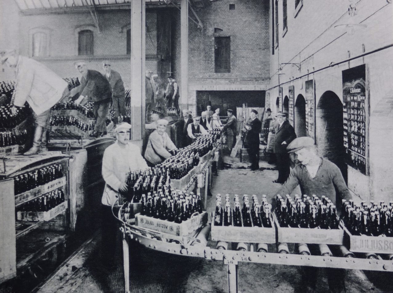 Arbeiter an der Produktionsstrecke der ehemaligen Bötzow-Brauerei Berlin, Flaschenkästen auf der Rollbahn